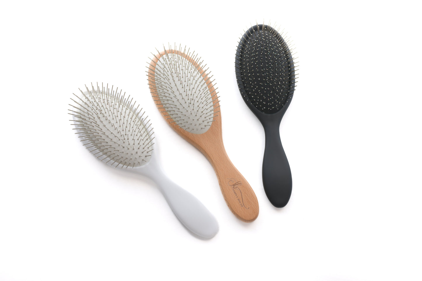 Three Simply Boujie detangling brushes standing upright in beechwood, matte black and pearl white